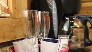 A basket containing two champagne flutes and a coffee cup with text, placed on a wooden surface. - Wild and Wonderful Wilderness Cabin! (Hico)