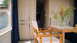 A room with a wooden table and chairs, a vase with flowers, and a view of a river. - Spreeapartment MARA (Berlin)