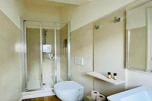 A modern bathroom with a glass-enclosed shower, a white toilet, and a sink with a mirror above it. - Appartamento Rossini (Como)