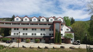 A multi-story hotel with a symmetrical facade, large windows, and a prominent glass entrance. - Gorgeous 3BR, 3BA Townhouse Right on the Pemi River - Great Views! (Lincoln)