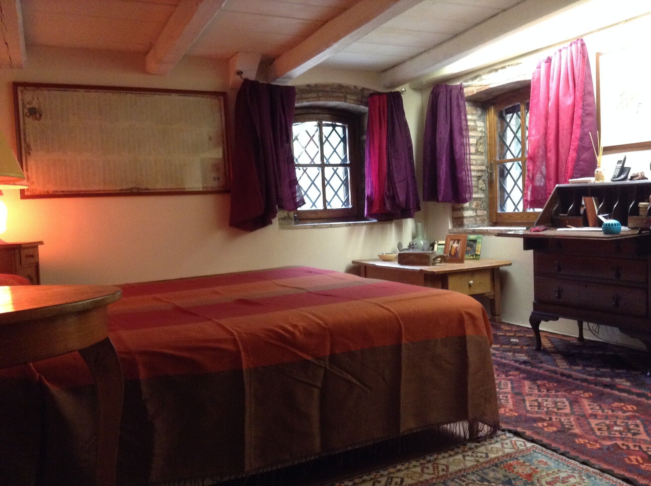 Una habitación con cama, escritorio, cómoda y ventana con cortinas.