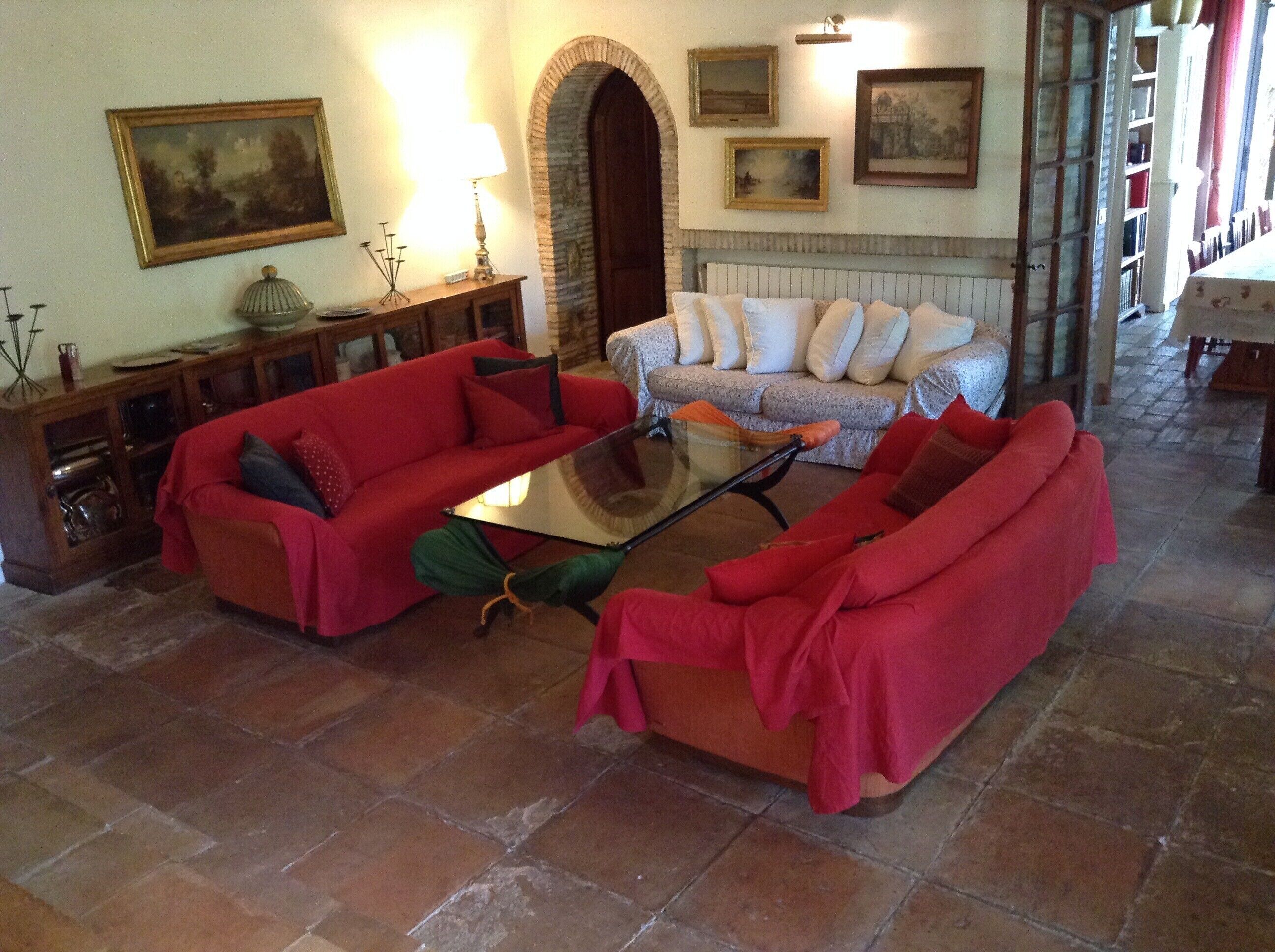 A cozy living room with two red sofas, a glass coffee table, and a stone fireplace.