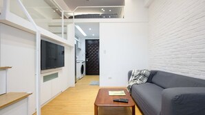 Um apartamento moderno com sala de estar, sofá, mesa de centro, televisão, cozinha e lavanderia.