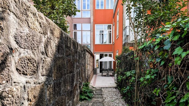 Un étroit sentier de pierres mène à un bâtiment à la façade rouge et doté de nombreuses fenêtres.