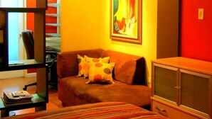 Une chambre avec une couvre-lit à rayures, un canapé avec des coussins, un tableau au mur et une armoire.