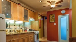 Une cuisine compacte avec des meubles en bois, une cuisinière et un coin repas agrémenté d’assiettes et de couverts.
