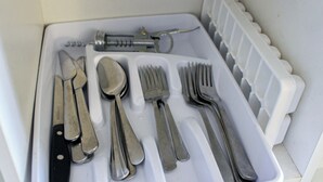 A white tray with a set of silverware including a knife, spoon, fork, and two forks, arranged neatly. - Cómodo apartamento en el casco de Ponce, diagonal a la plaza (Ponce Pueblo)
