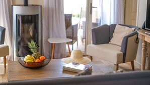 Un salón acogedor con chimenea, una mesa de comedor con fruta y un libro, y un sofá cómodo.