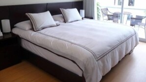 A neatly made bed with a dark headboard and white bedding. - LUXURY APARTMENT IN MIRAFLORES, LIMA, PERU, 2 BEDROOMS WITH JACUZZI (Miraflores)