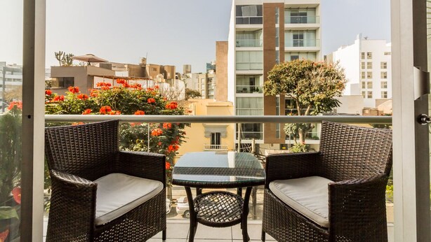 A balcony with wicker furniture and a view of the cityscape. - LUXURY APARTMENT IN MIRAFLORES, LIMA, PERU, 2 BEDROOMS WITH JACUZZI (Miraflores)