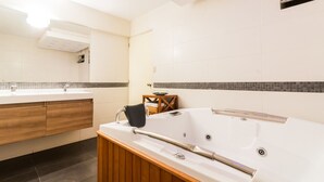 A modern bathroom with a wooden vanity, a large bathtub, and a mirror. - LUXURY APARTMENT IN MIRAFLORES, LIMA, PERU, 2 BEDROOMS WITH JACUZZI (Miraflores)