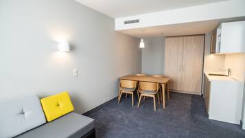 Ein kompakter Wohnraum mit Sofa, Esstisch und Stühlen, einer Küchenzeile und einem Kleiderschrank.