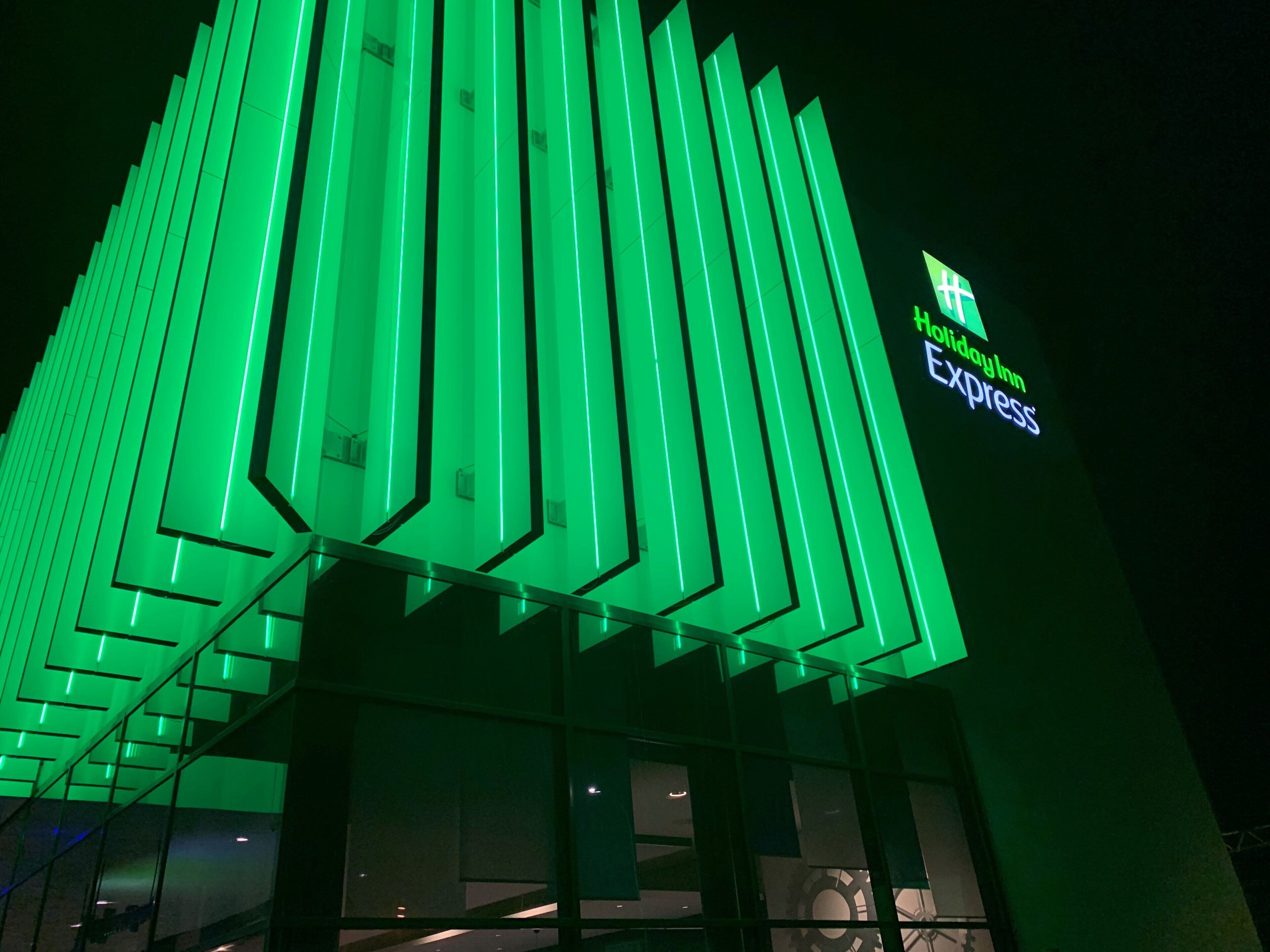 A building with vertical green lighting and a sign for Holiday Inn Express.