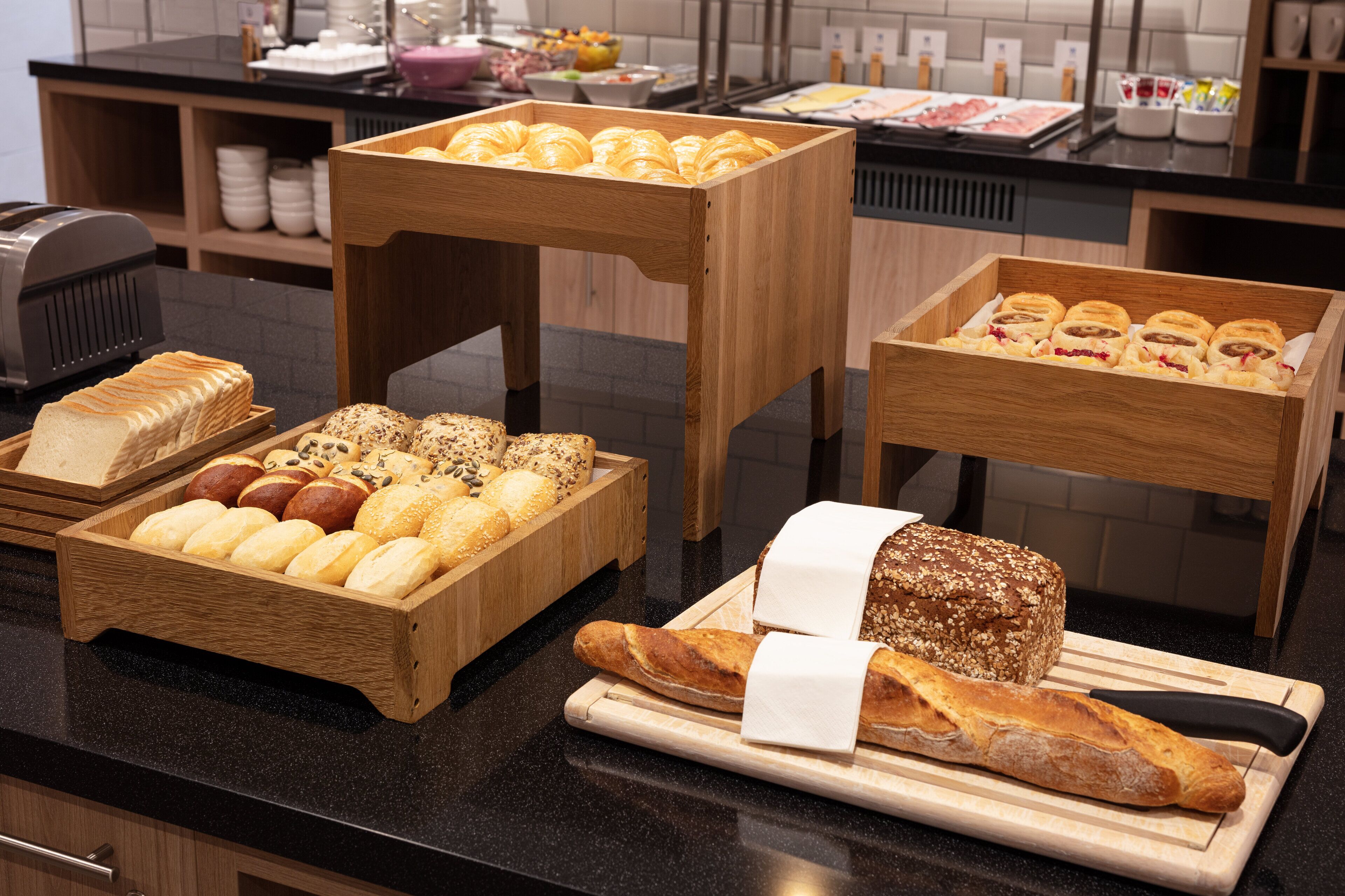 Une variété de produits de boulangerie présentés sur des présentoirs en bois dans une cuisine.