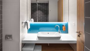 A modern bathroom with a white sink, blue accent wall, and a wooden vanity.