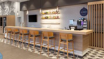 A modern bar area with a long counter, multiple stools, and a variety of bottles on shelves.