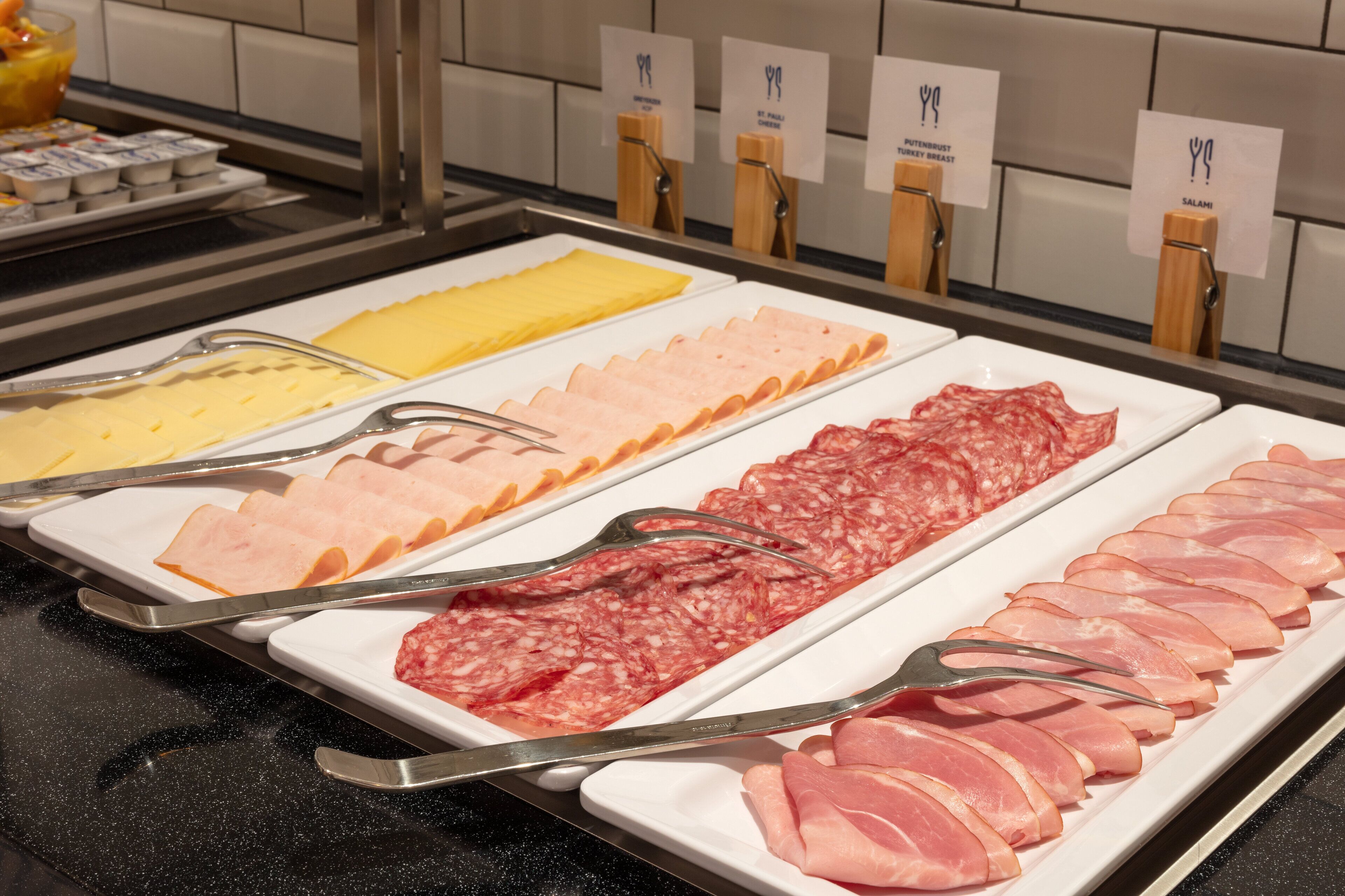 A buffet with various meats and cheeses.