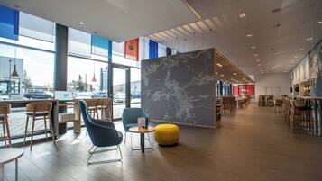 A modern interior with seating areas, a map display, and large windows offering views of the city.