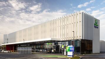 A modern Holiday Inn Express hotel with a large glass facade and a prominent green logo.