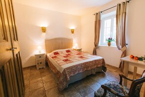 A bedroom with a bed, bedside tables, a window with curtains, a small table with flowers, and a chair. - Vacation rental house with pool LIOUX LS2-92 (Lioux)