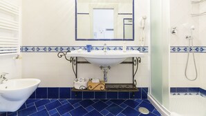 Een badkamer met een wit wastafel, een spiegel, een toilet en een douche.
