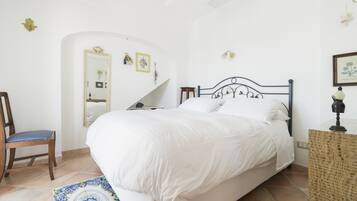 Una camera da letto con un letto grande, una sedia, un tavolino e uno specchio decorativo.