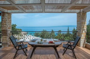 A terrace with a table set for two, overlooking a scenic view of the sea and greenery. - 2 Bedroom Suite Sea View with Jetted Tub (Paxoi)