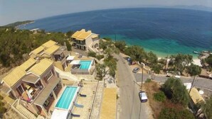 A coastal residential area with houses, a swimming pool, and a road leading to the sea.