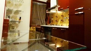 A modern kitchen with a glass railing, stainless steel appliances, and a red accent wall. - Casa Vita Bella - Apartment on the Flower Riviera - quality for good price (Diano San Pietro)