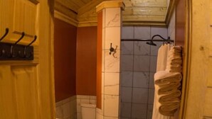 A wooden interior with a toilet, shower, and towel rack. - Cozy Bear Log Cabin Tri-Valley  (Healy)