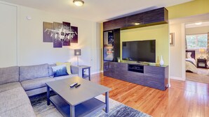 Ein modernes Wohnzimmer mit Ecksofa, Couchtisch, Flachbildfernseher und einer integrierten Unterhaltungseinheit.