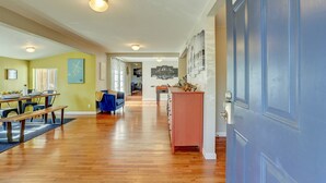 Ein geräumiger Wohnbereich mit Holzdielen, einem Esstisch mit Bänken, einem blauen Sofa und einem roten Schrank.