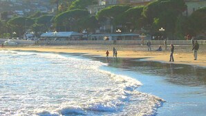 A beach with people walking along the shore, a sandy beach, and buildings in the background. - Casa Sole - Vacation apartments on the Flower Riviera, decorated with love (Diano San Pietro)