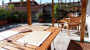 A wooden table with woven mats, a wooden chair, and a pergola structure. - Casa Sole - Vacation apartments on the Flower Riviera, decorated with love (Diano San Pietro)