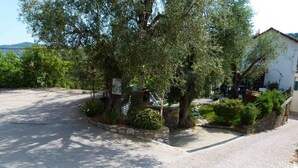 A paved courtyard with a stone wall, trees, and a sign. - Casa Sole - Vacation apartments on the Flower Riviera, decorated with love (Diano San Pietro)