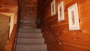 A wooden staircase with carpeted steps and a handrail, leading to a lower level. - Mountaineer Relaxing 2 Bedroom Cabin  (Hico)