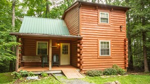 A log cabin with a porch, a small front entrance, and a wooden bench. - Mountaineer Relaxing 2 Bedroom Cabin  (Hico)