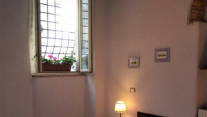 A bedroom with a bed, a window with a view of pink flowers, a bedside lamp, and two framed pictures on the wall. - Apartment - Silver Sunset (Manciano)