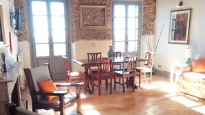 A rustic room with a stone wall, wooden ceiling beams, a dining table with chairs, a sofa, and a painting on the wall. - Apartment - Silver Sunset (Manciano)