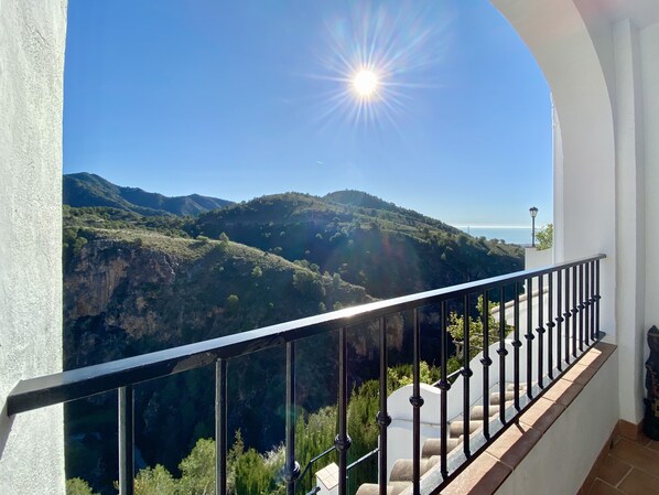 A balcony with a view of a mountainous landscape and the sea.