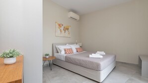 A modern hotel room with a bed, a small table, and a potted plant.