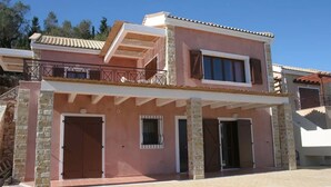 A two-story house with a balcony, a covered entrance, and a stone facade. - 3 Bedroom Pool Suite Sea View (Paxoi)
