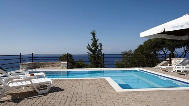 A pool area with lounge chairs and a view of the sea. - 3 Bedroom Pool Suite Sea View (Paxoi)