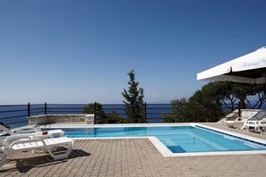 Zona de piscina con sillones de descanso y vista al mar.