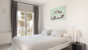 A modern bedroom with a bed, a nightstand, a lamp, and a window with curtains.