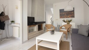 A modern living room with a fireplace, white furniture, and a cityscape painting.