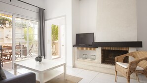 A modern living room with a fireplace, a television, and a dining area with outdoor seating.