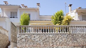 A multi-story building with a stone facade, balconies with railings, and a clear sky.