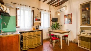 Une cuisine avec une table en bois, des chaises, un évier, un four à micro-ondes et un téléviseur.