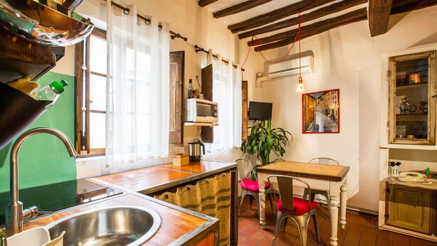 Une cuisine équipée d’un évier, d’un four à micro-ondes, d’une table avec des chaises et d’un tableau accroché au mur.
